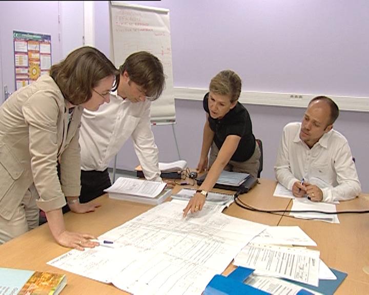 L'Ineris vous assiste pour la mise en place et l'évaluation des performance de vos barrières de sécurité. 4 personnes autour d'une table travail sur un dossier. L'une d'elle montre quelque chose sur un plan.