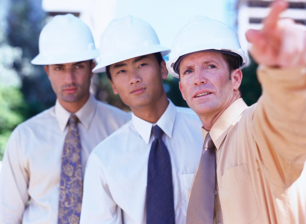 3 hommes discutent. Ils portent un casque de protection