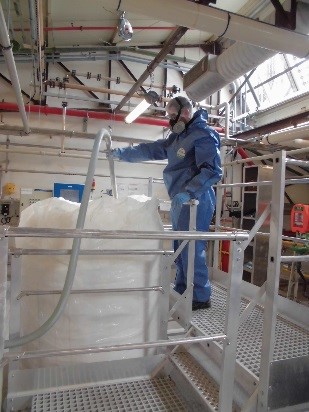 Photo d'un technicien remplissant un big bag. Cette opération génère des chages électrostatiques.
