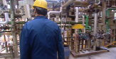 Employé d'usine marchant dans l'usine près de tuyaux